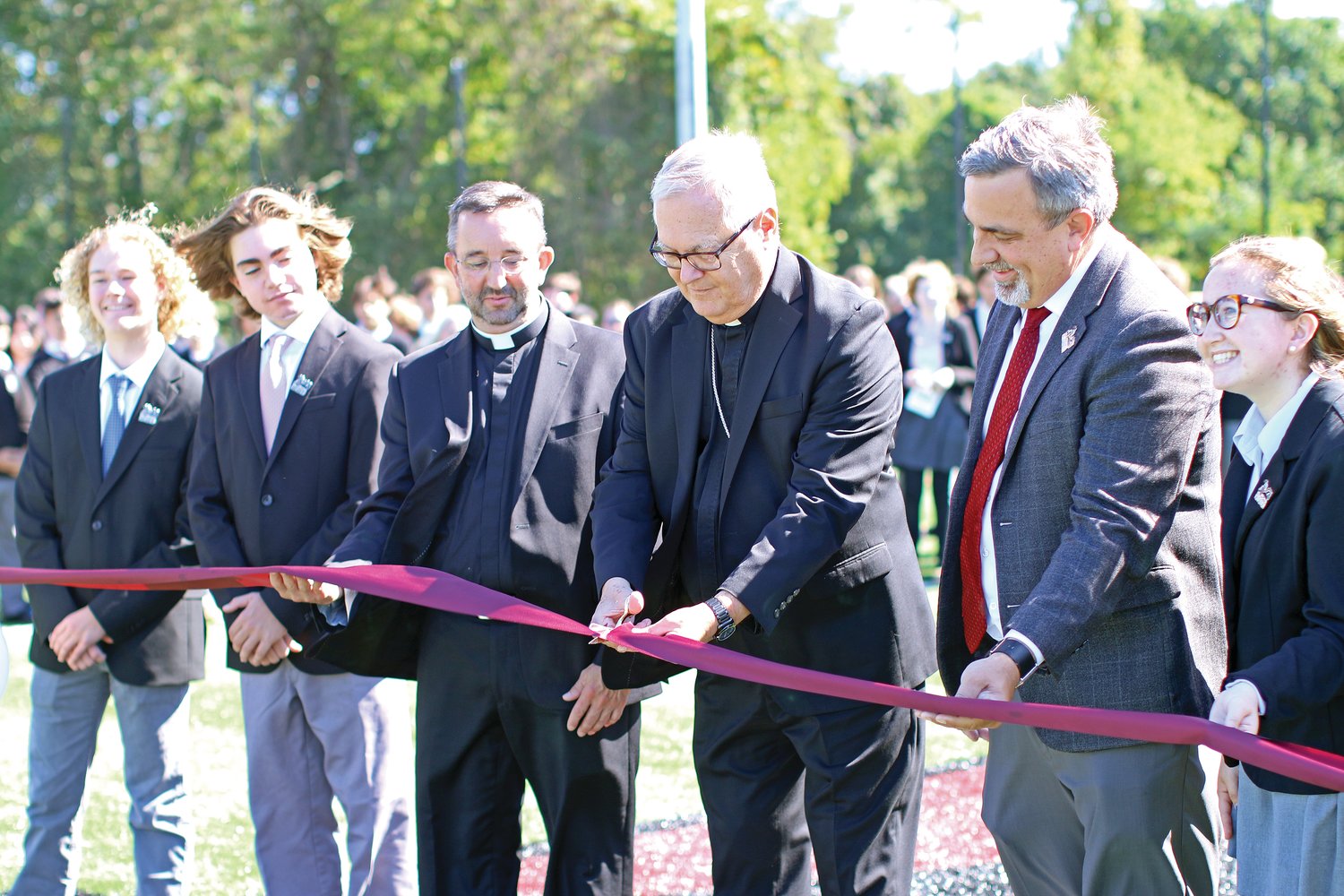 Bishop Thomas J. Tobin joins The Prout School Principal David Estes, right, Father Carl Fisette, school chaplain, left, and students in the dedication and blessing of The Meghan C. Cooney Field on Wednesday, Sept. 14 in Wakefield.